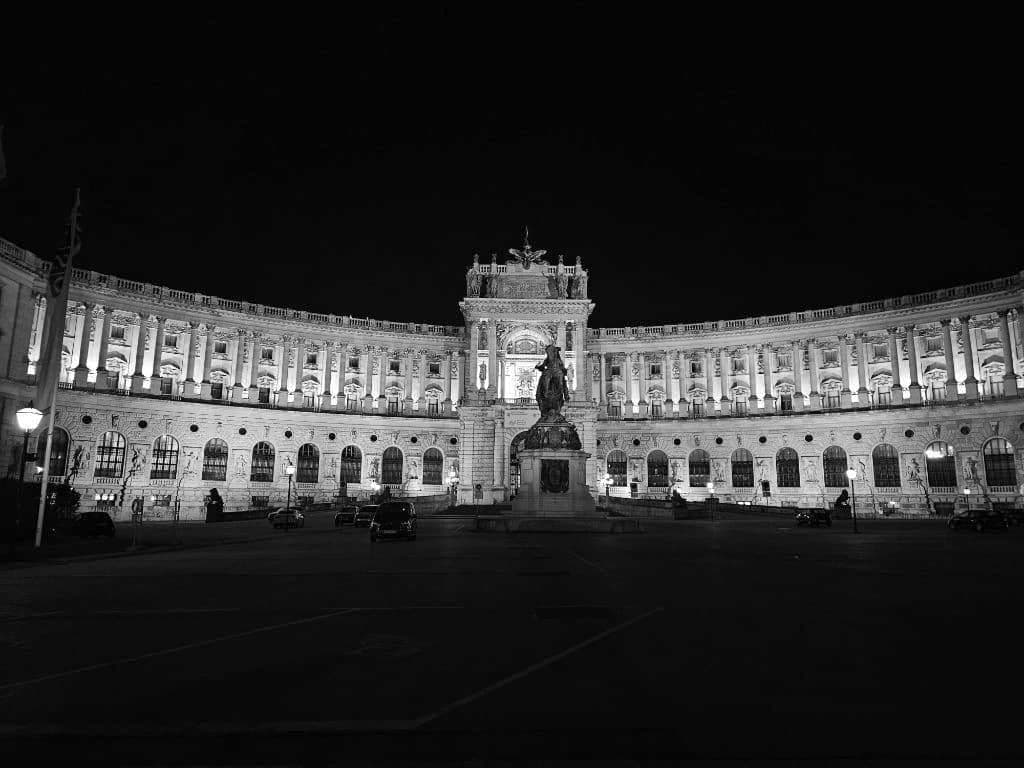 Neue Burg Hofburg Sarayı'nın gece aydınlatılmış kavisli cephesi ve atlı heykel.
